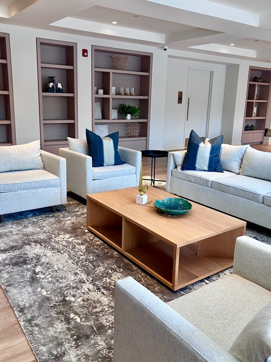 Four cream swivel chairs around a round marble table in a sunlit residential amenity space.