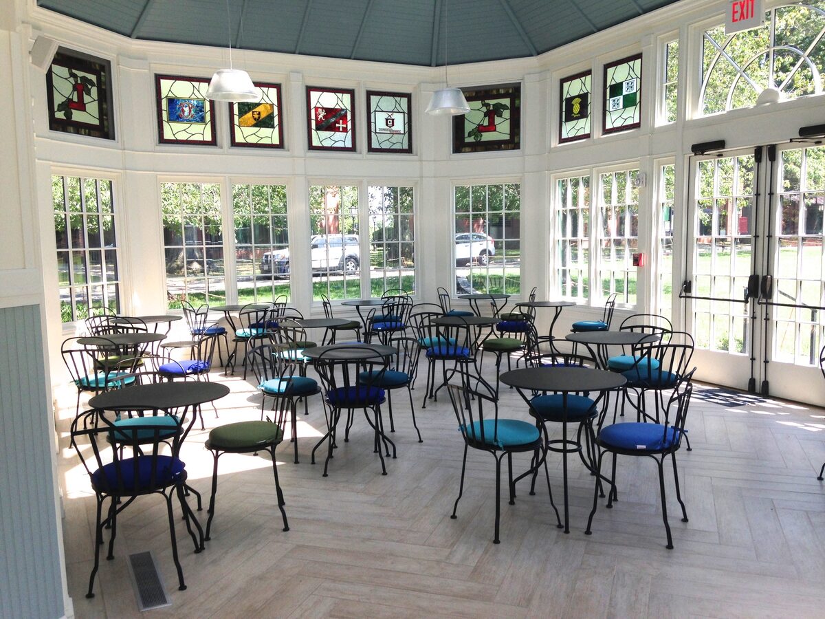 A glass conservatory with stained-glass accents and intimate cafe-style seating.