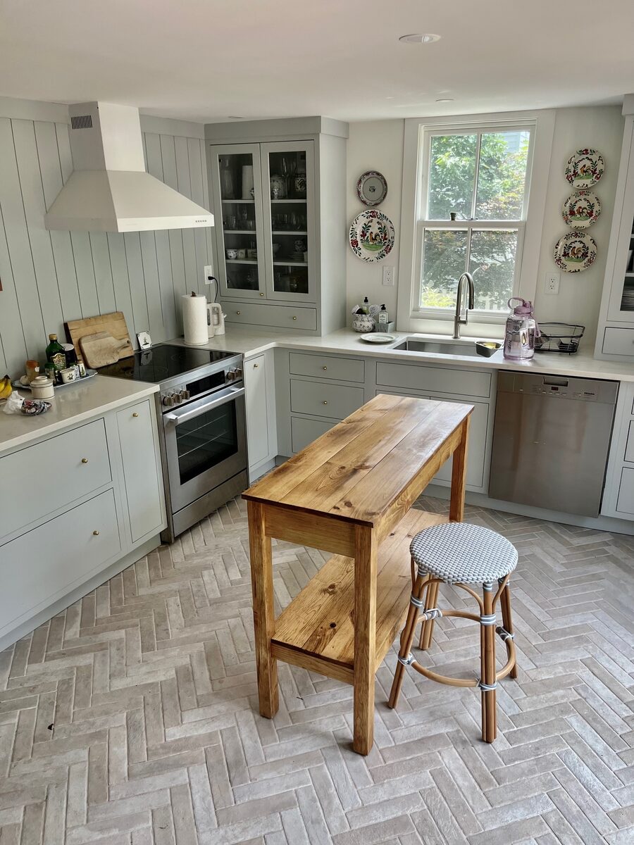A wider view of the cottage kitchen with herringbone brick floors and a heron print.