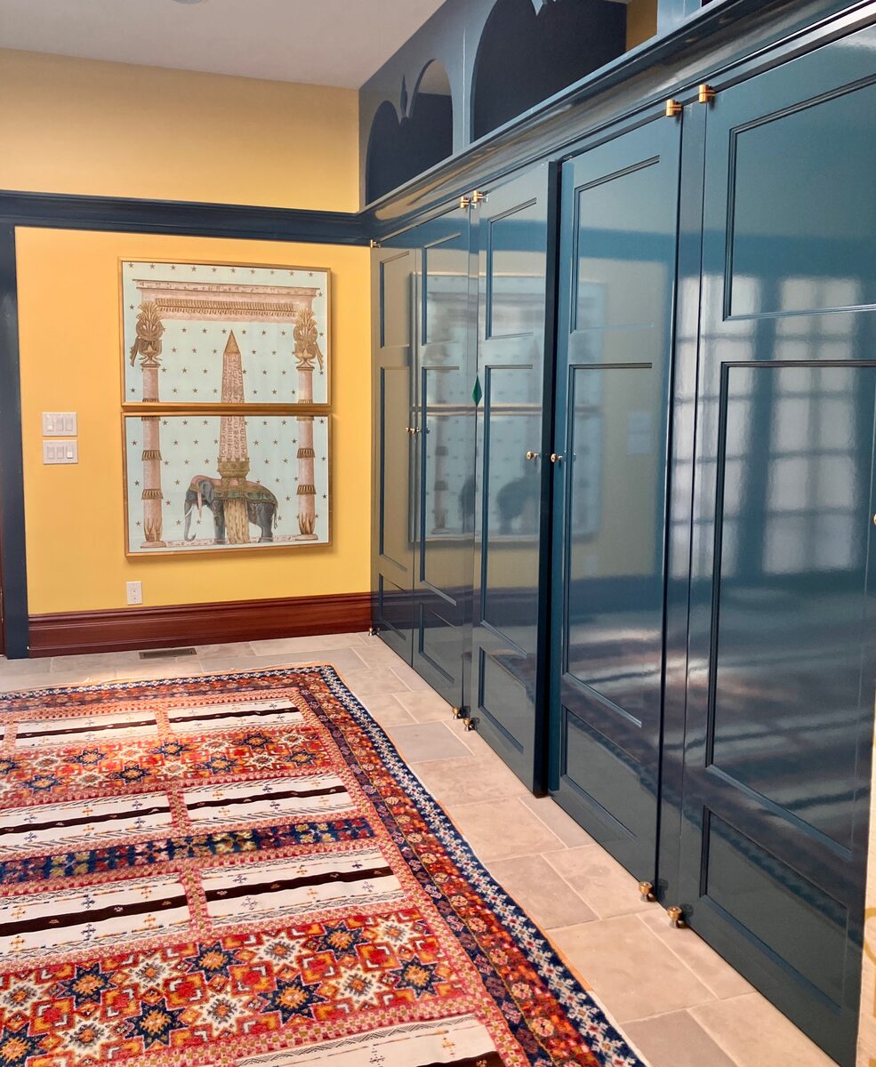A welcoming entry with custom teal display cabinetry, framed art, and a layered kilim runner.