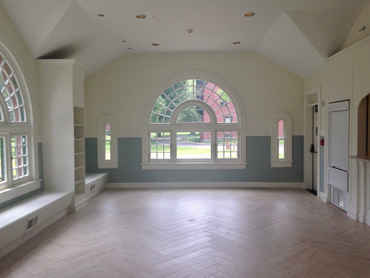 A light-filled great room with a Palladian window, built-in window seats, and herringbone floors.