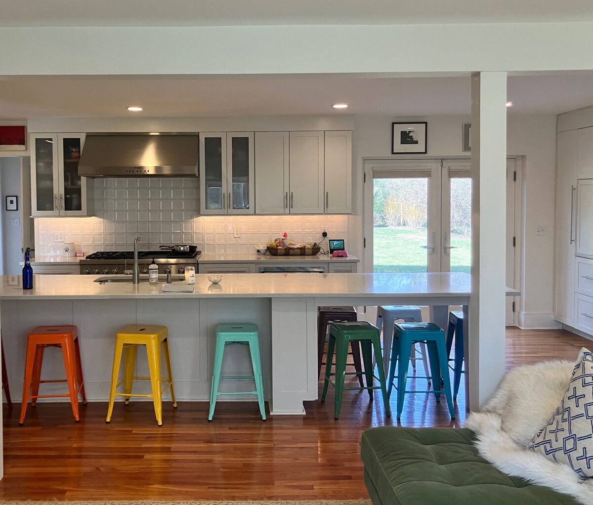 An open kitchen opening to the garden, energized by a row of brightly colored counter stools.
