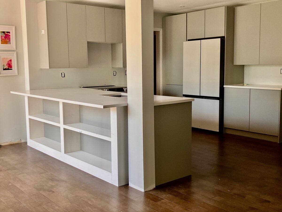 A freshly built kitchen in soft sage, captured before styling with new cabinetry and open shelving.