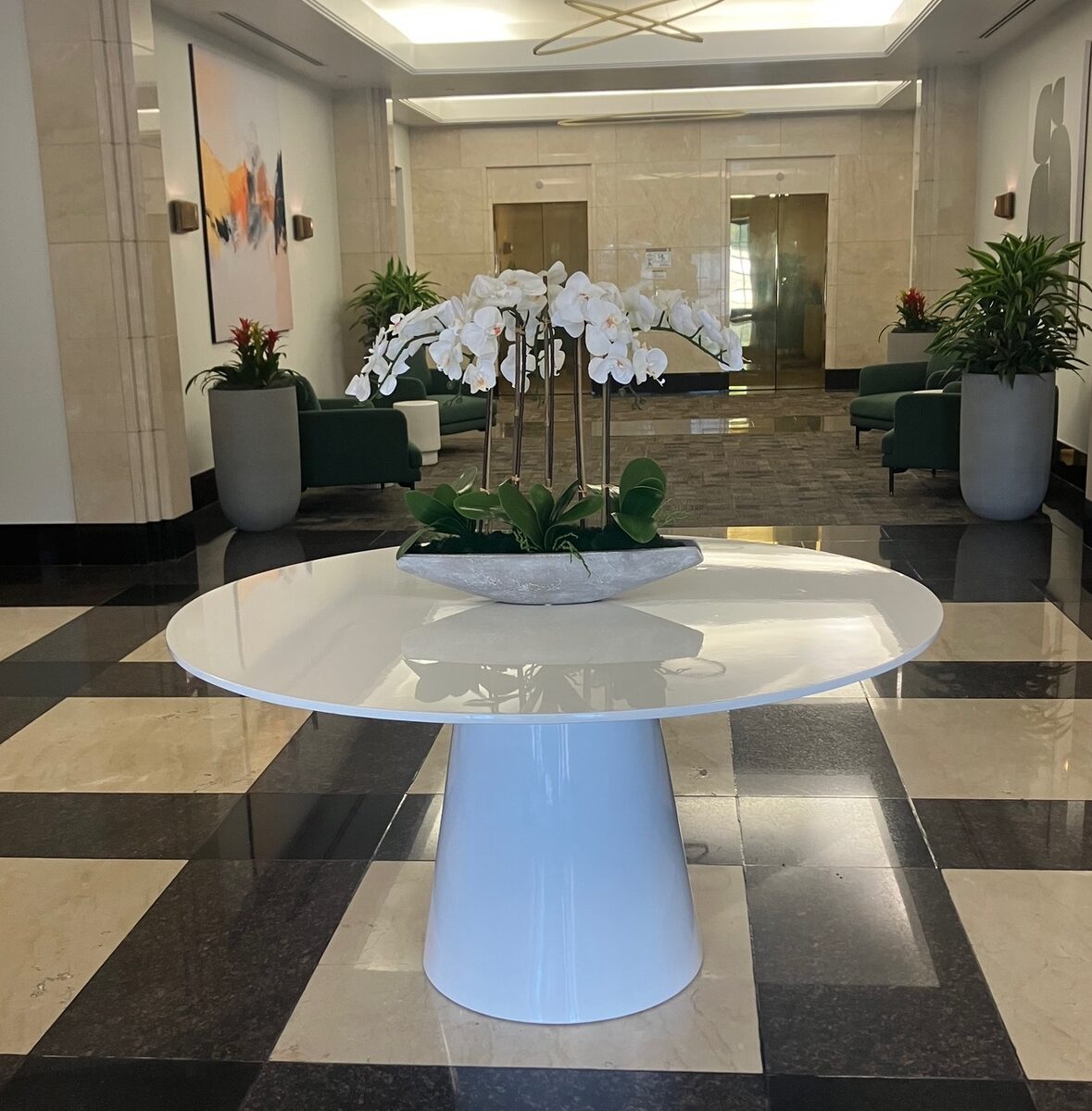 A polished lobby entry with a checkerboard marble floor and a sculptural orchid centerpiece.